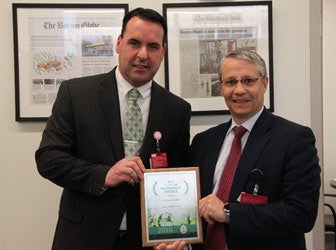 Two gentlemen holding the Emerald Award from Practice Greenhealth