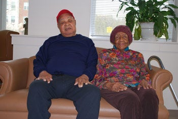 two older individuals, a man and a woman, sitting on the couch